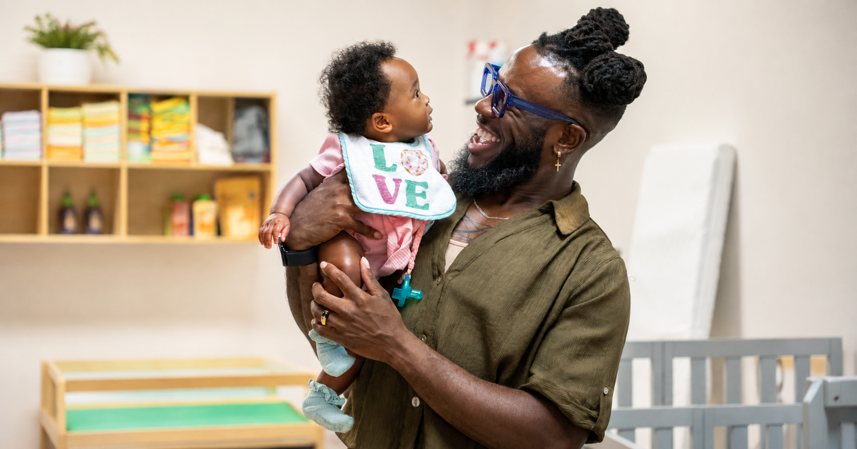 A teacher smiling while holding an infant in the Foundations Division at The Early Learning Institute